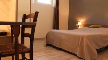 Ein Schlafzimmer mit einem Bett, einem Sessel, einem Tisch und einer Lampe.