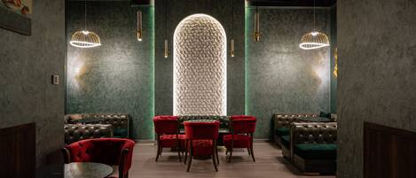 A modern interior with a central seating area, a unique textured wall, and pendant lighting.
