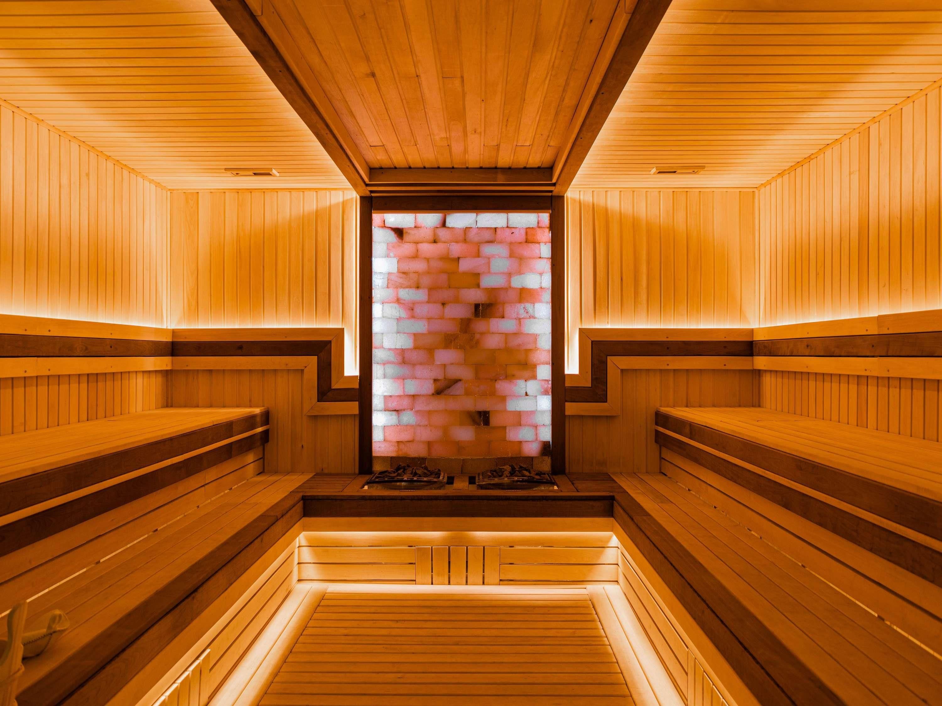 A sauna with wooden benches and a brick wall.