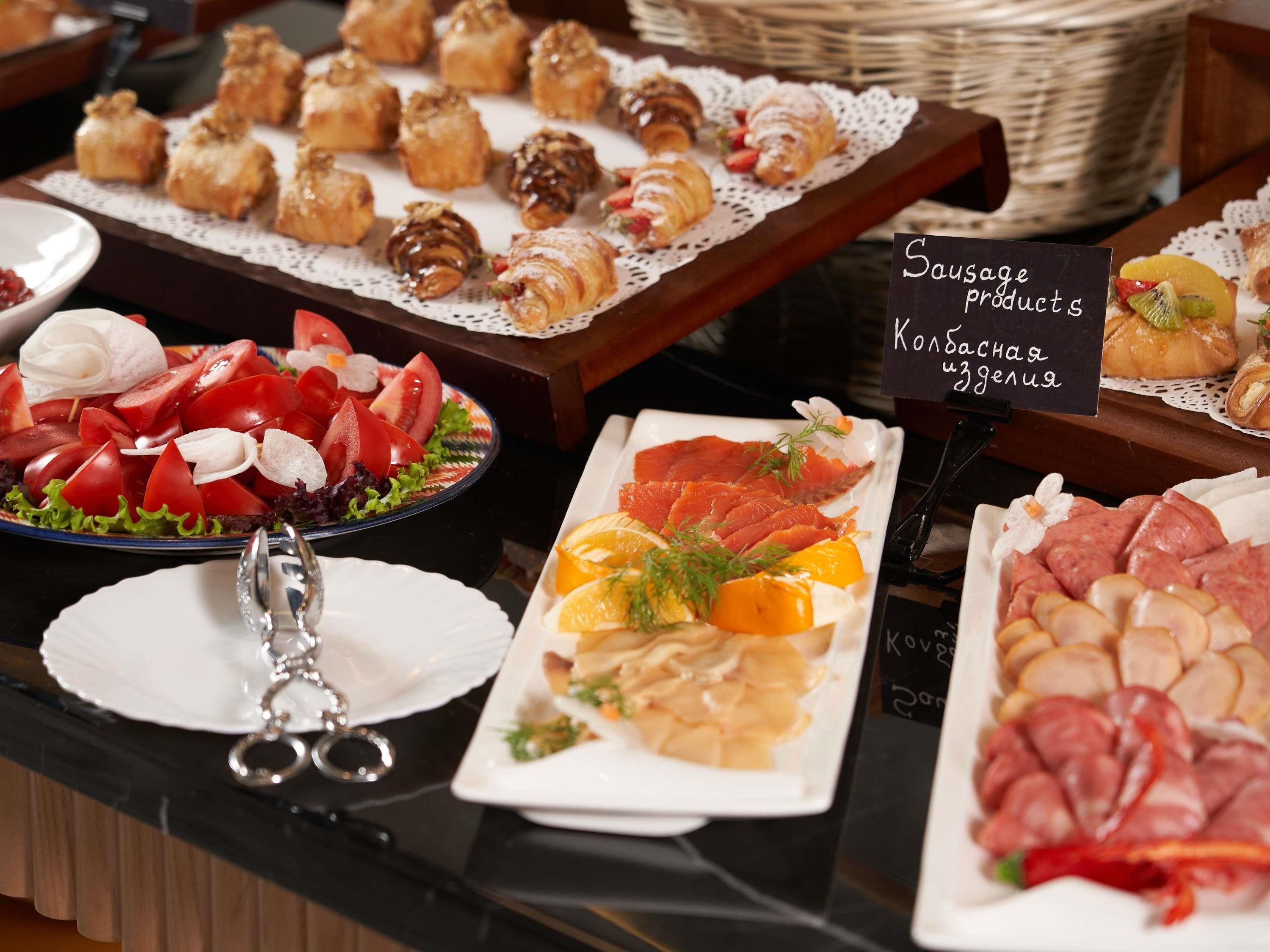 En buffet med forskellige retter, herunder salater, kød og bagværk.