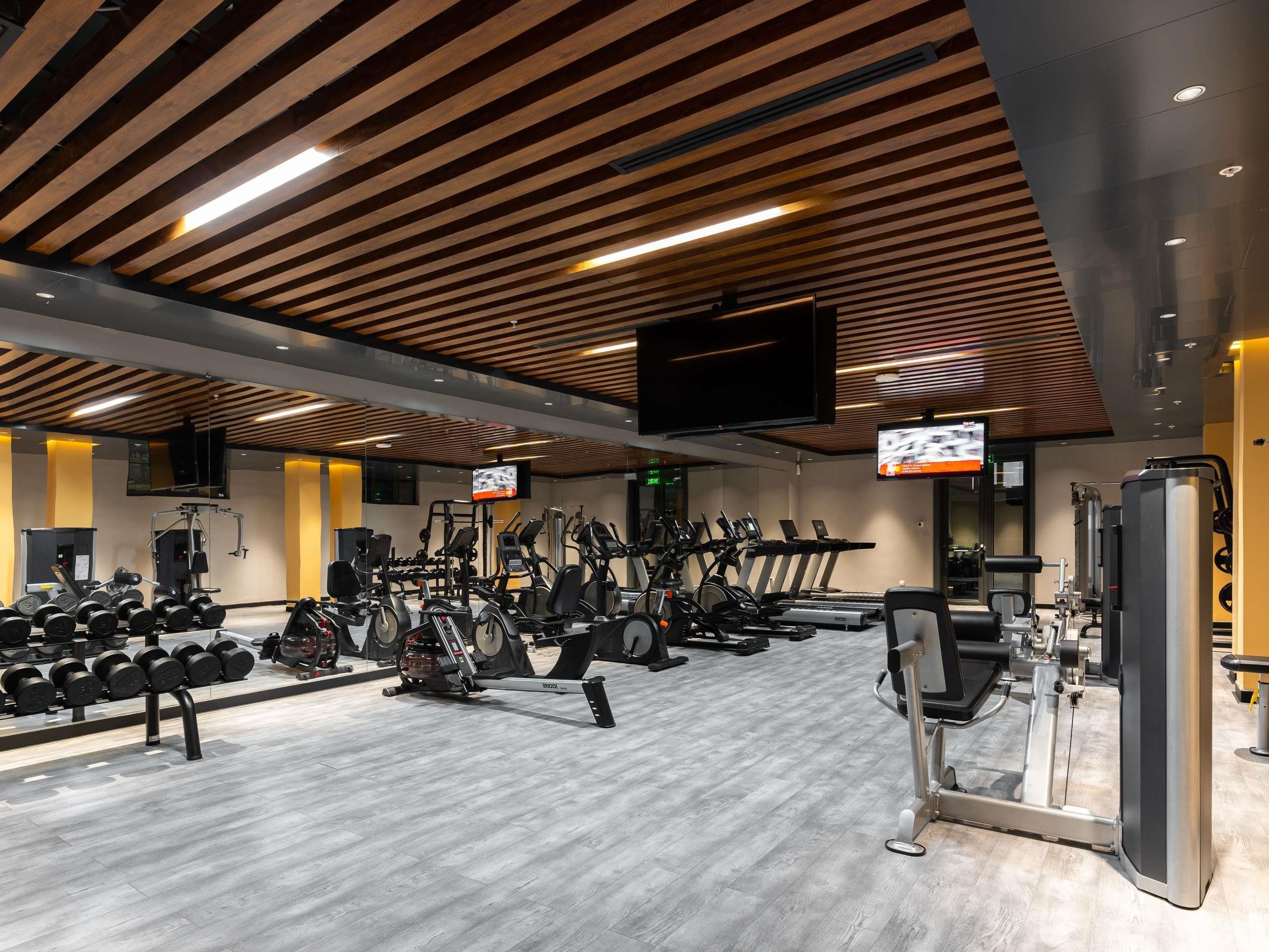 Un gimnasio con equipo de ejercicio, televisión y techo de madera.