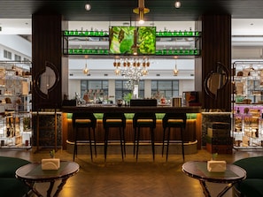 A bar area with a TV screen, bar stools, and a chandelier. - Mövenpick Samarkand (Samarkand)