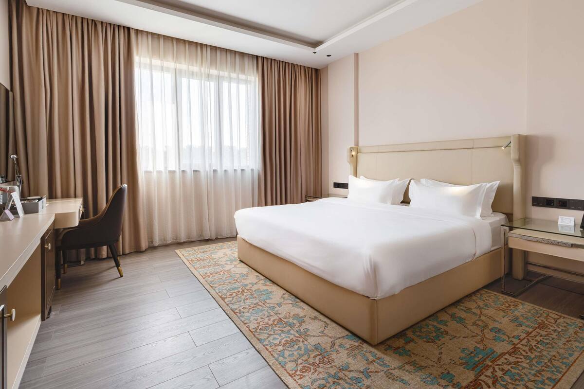 A hotel room with a large bed, a desk, and a chair.