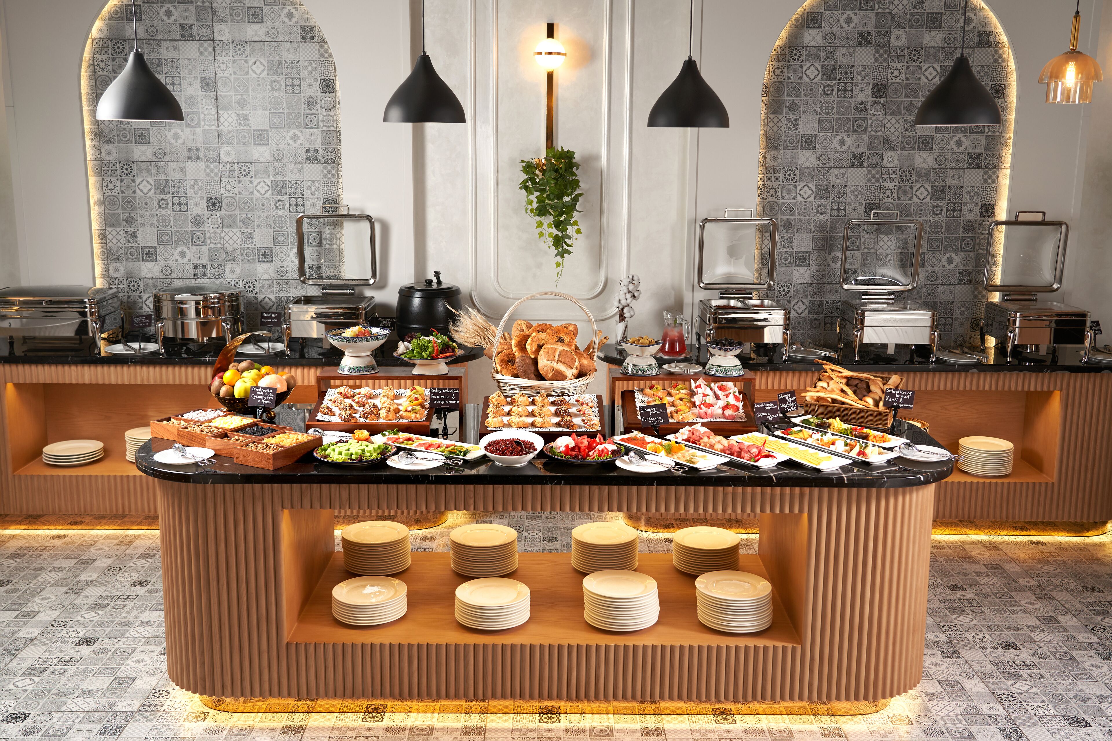 A buffet setup with various food items and utensils, including plates, bowls, and serving dishes.