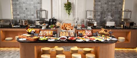 A buffet setup with various food items and utensils, including plates, bowls, and serving dishes.