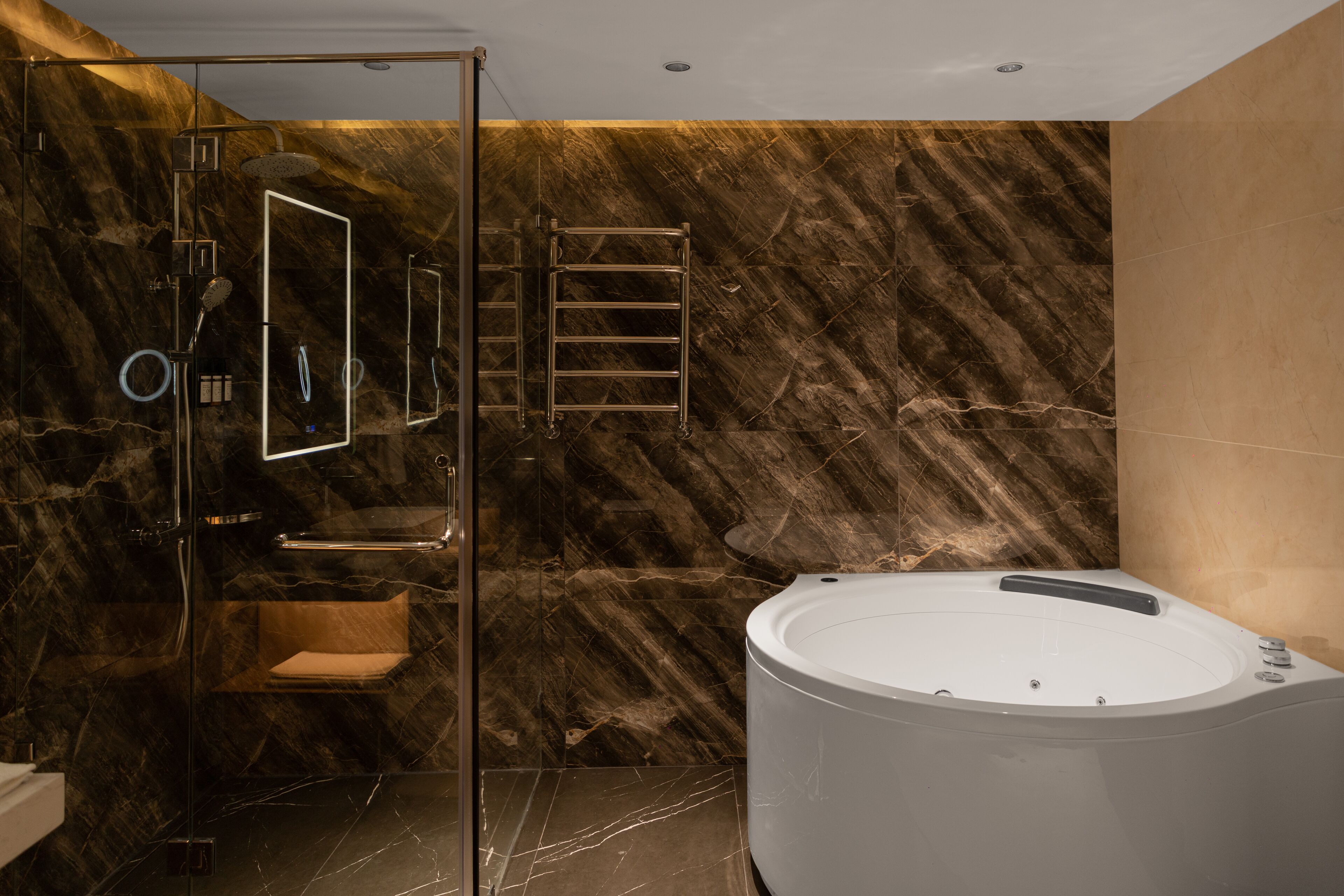 A modern bathroom with a glass-enclosed shower, a freestanding bathtub, and marble walls.