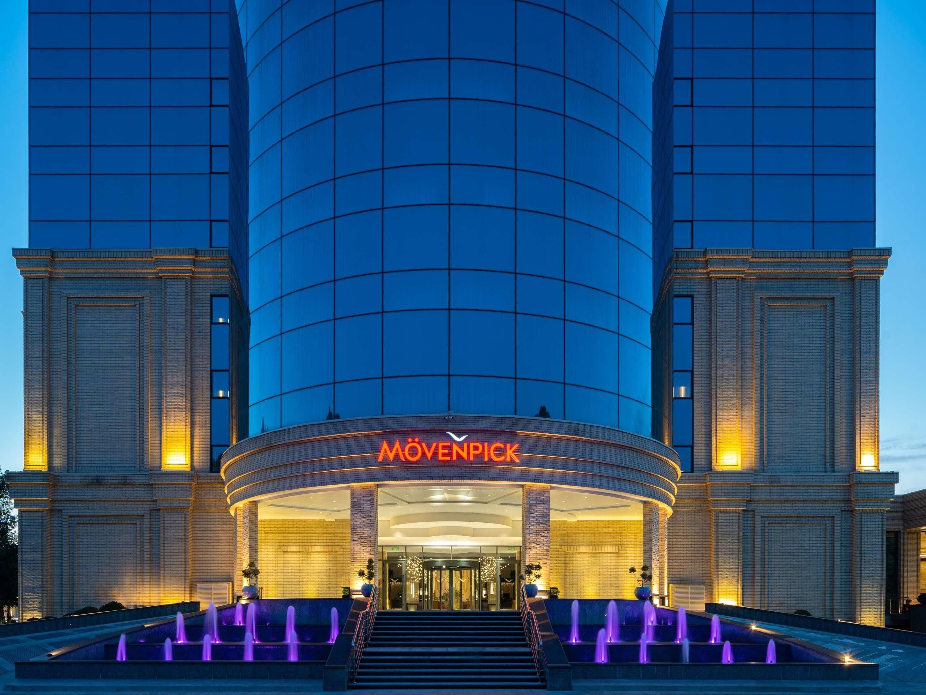 A modern hotel with a curved facade, a prominent entrance, and a fountain area.