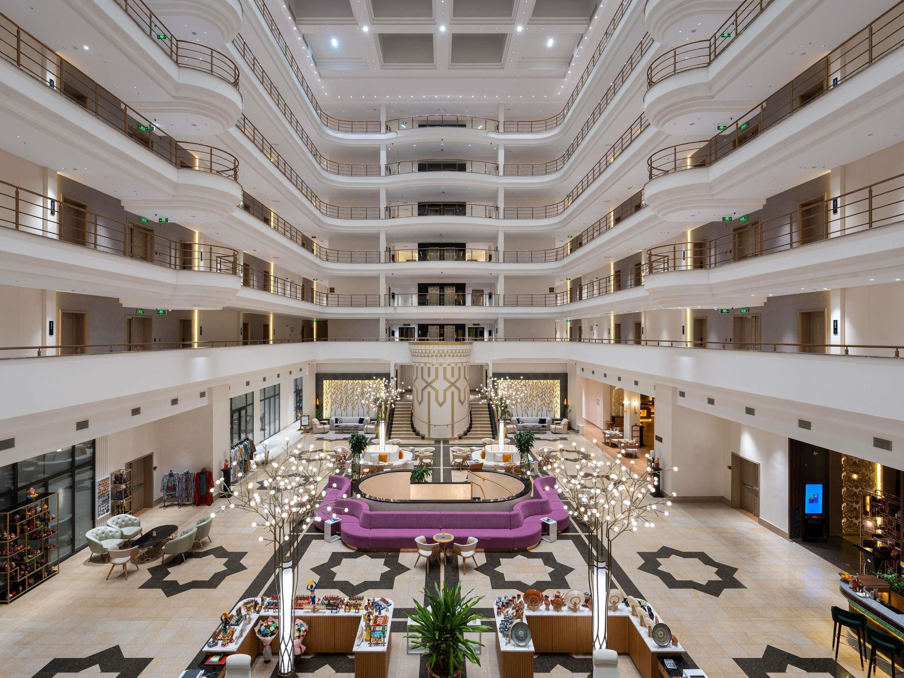 A multi-level atrium with a central circular seating area, multiple floors, and a variety of seating arrangements.