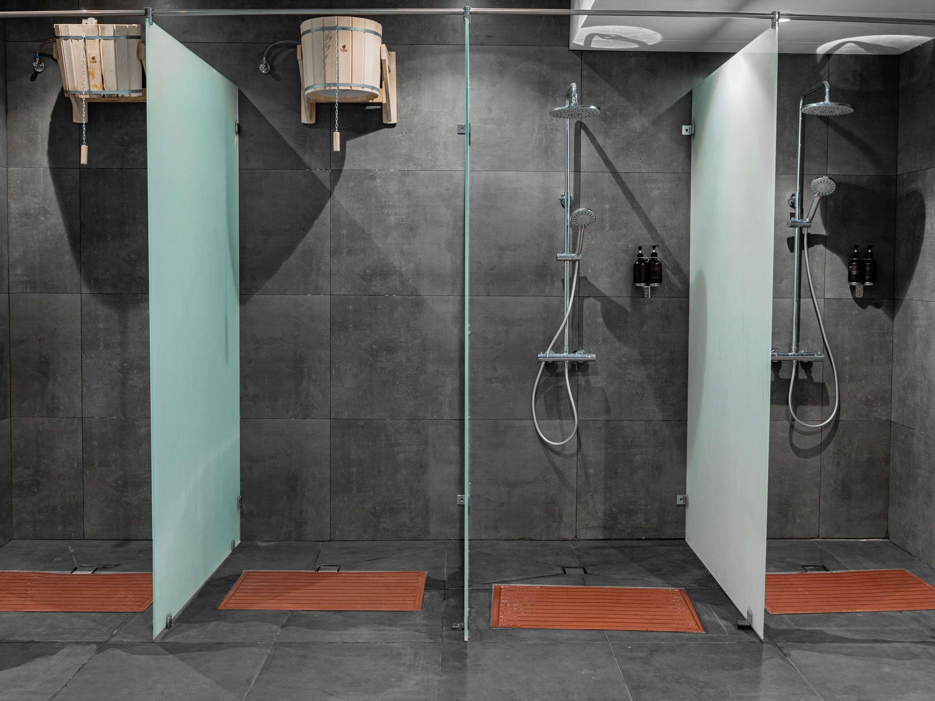 A modern bathroom with two separate shower stalls, each equipped with a handheld showerhead and a wall-mounted faucet.