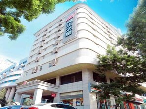 Un hotel de varios pisos con un diseño arquitectónico moderno, que presenta una fachada curva y varios balcones.