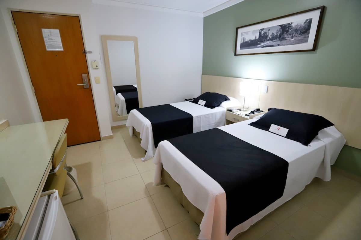 A hotel room with two beds, a desk, and a chair.