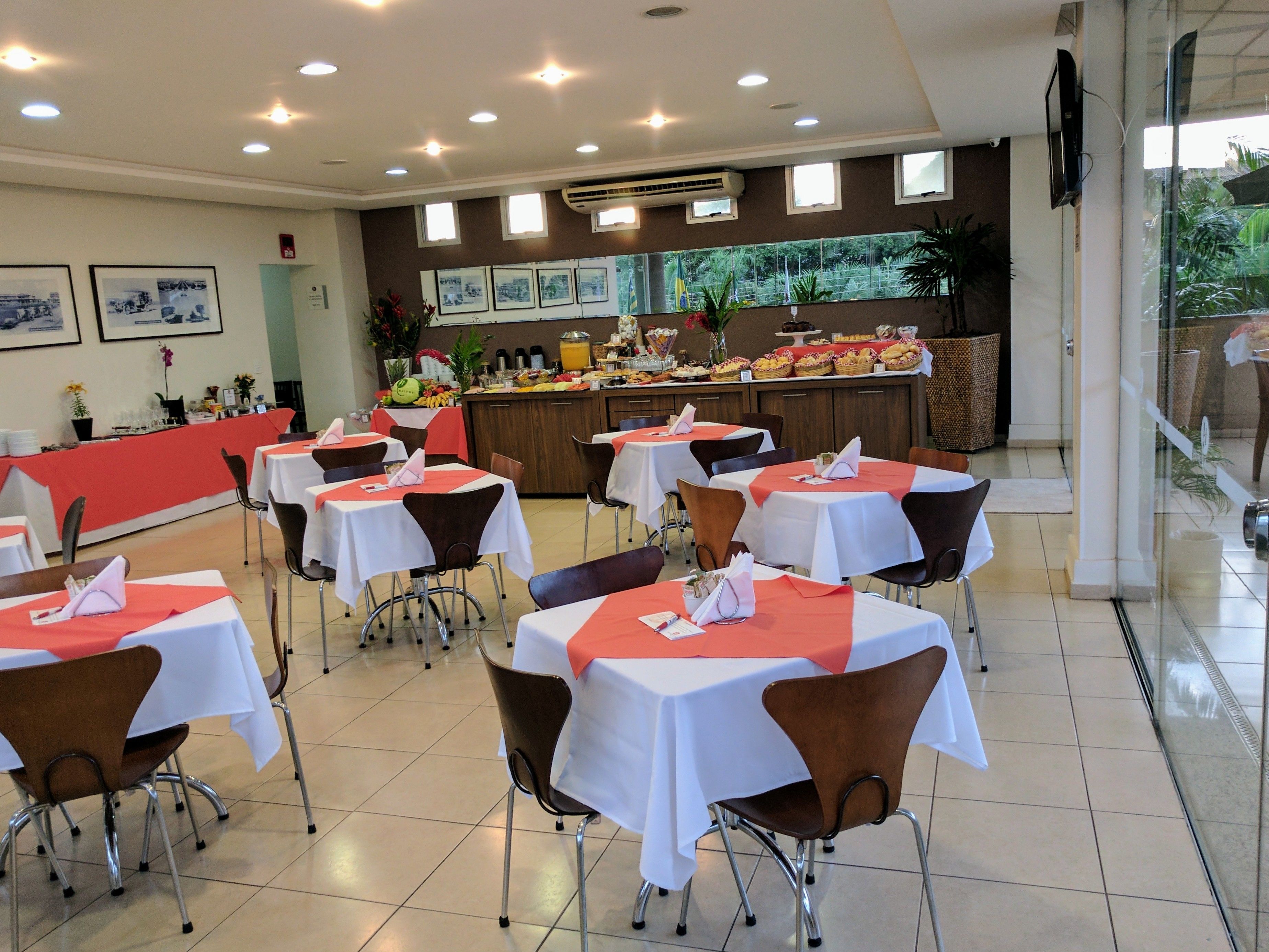 Un restaurant amb taules preparades per dinar, una zona de menjar a granel amb diversos plats i una cuina al fons.