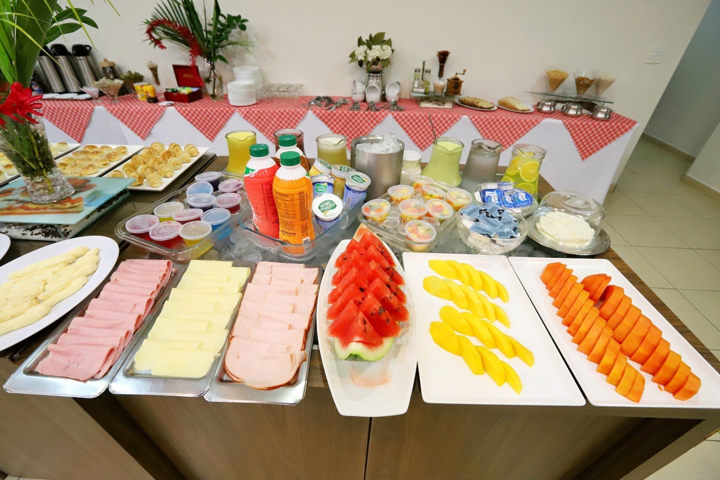 A buffet table with various food items including meats, cheeses, fruits, and beverages.