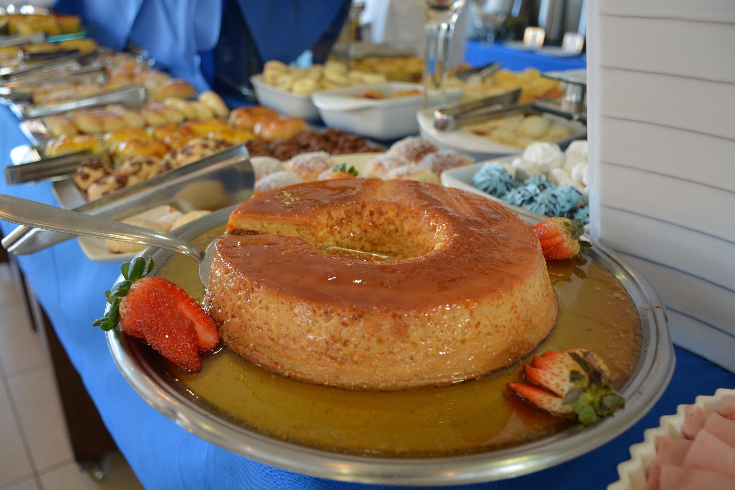 En buffet med flere retter, heriblandt en karamel flan på et sølvfad.