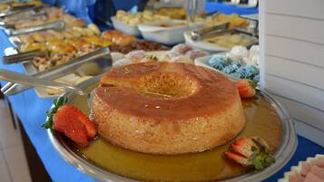 En buffet med flere retter, heriblandt en karamel flan på et sølvfad.