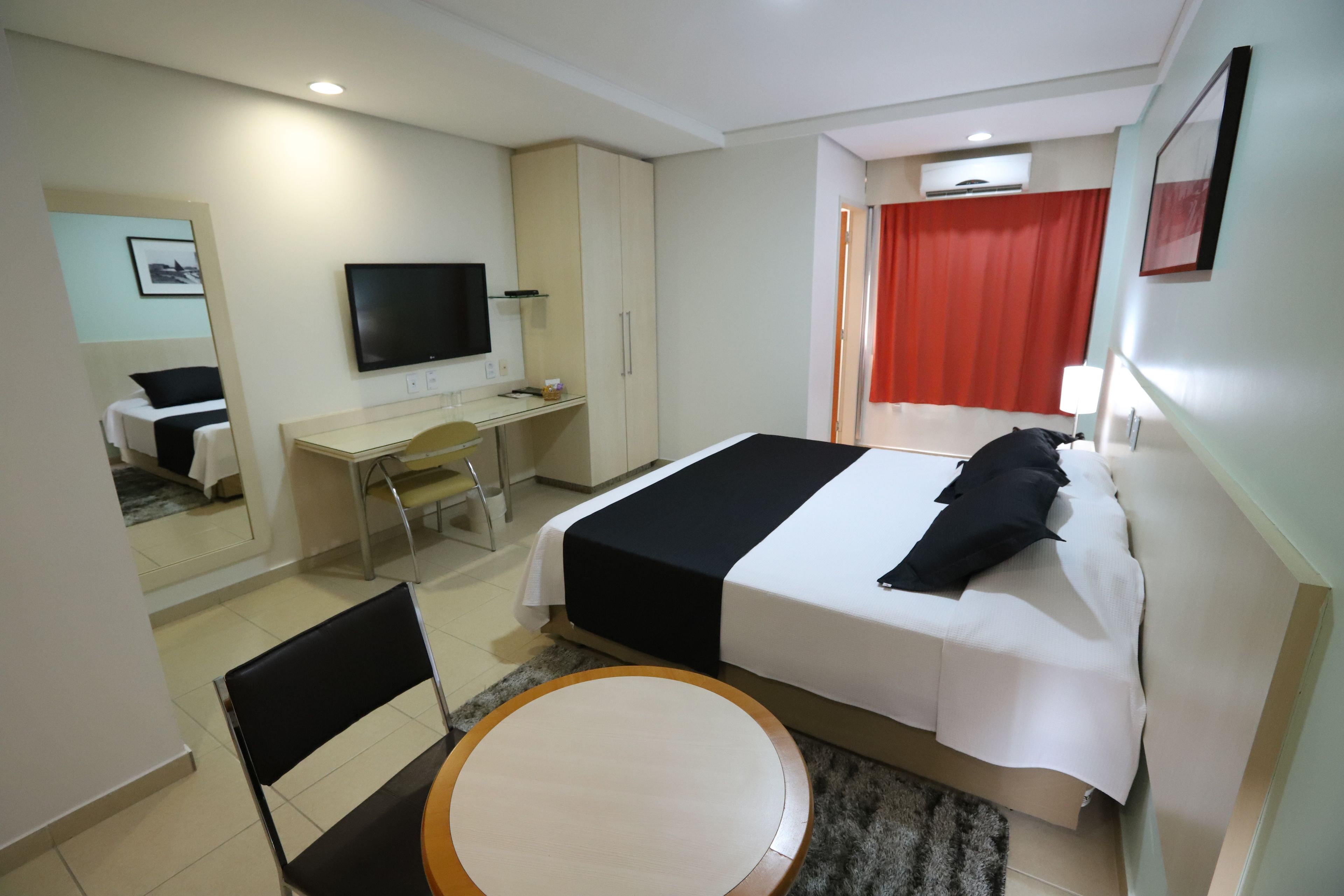 Habitació d'hotel amb un llit, escriptori, cadira, televisió i taula rodona.