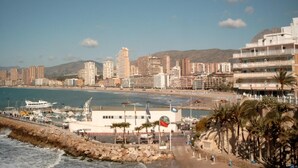 A coastal cityscape with a marina, buildings, and a rocky shoreline. - Jaime I (Benidorm)