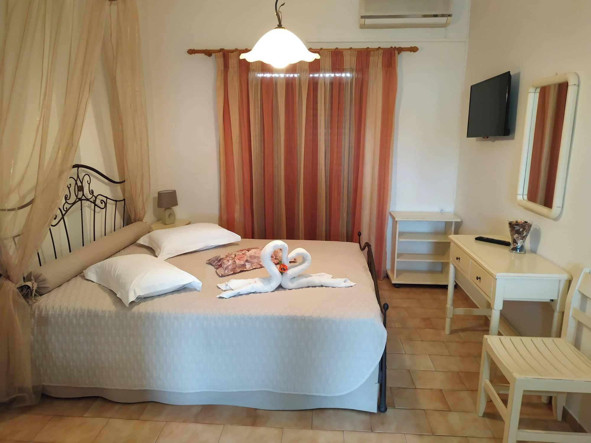 Una camera da letto ordinata con un letto, comodino, televisore e specchio.