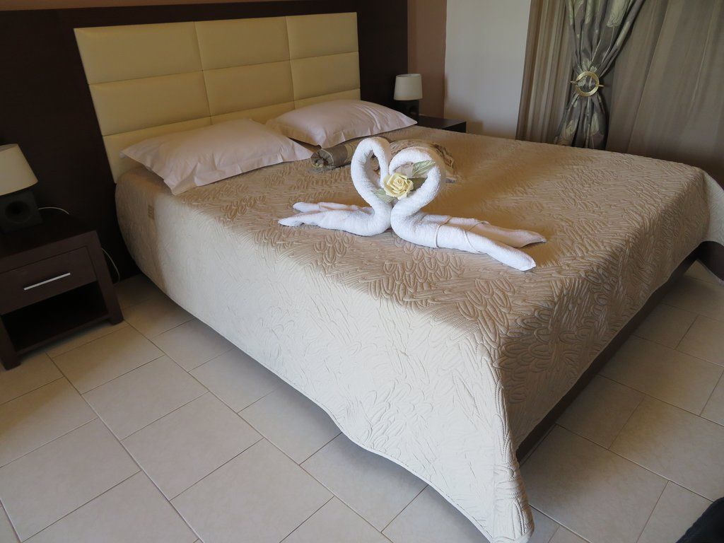 A hotel room with a bed, a nightstand, a lamp, and a swan-shaped towel decoration.