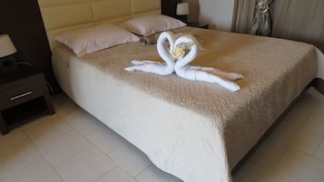 A hotel room with a bed, a nightstand, a lamp, and a swan-shaped towel decoration.