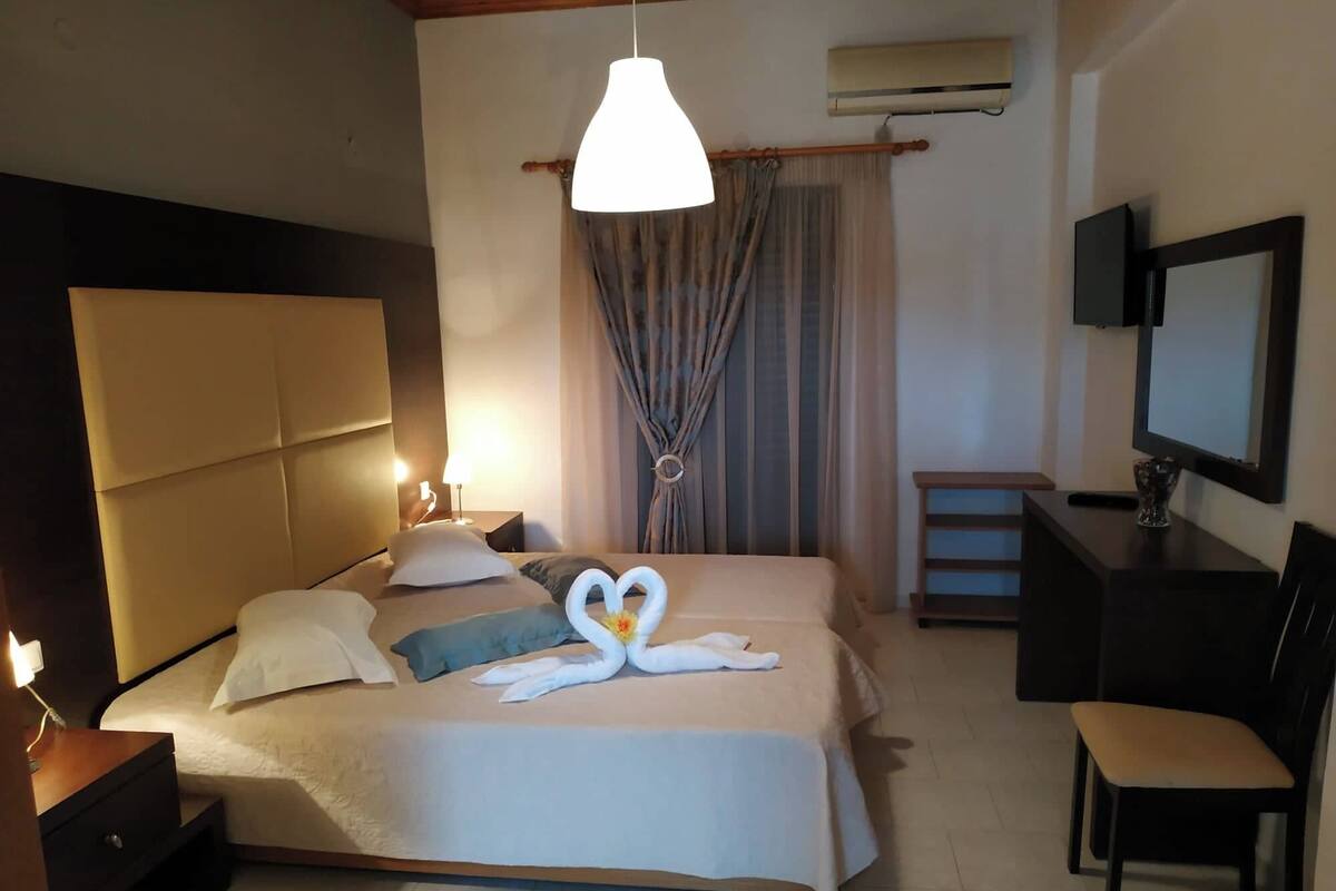 Une chambre d’hôtel avec un lit, des lampes de chevet, une télévision, un bureau et une chaise.