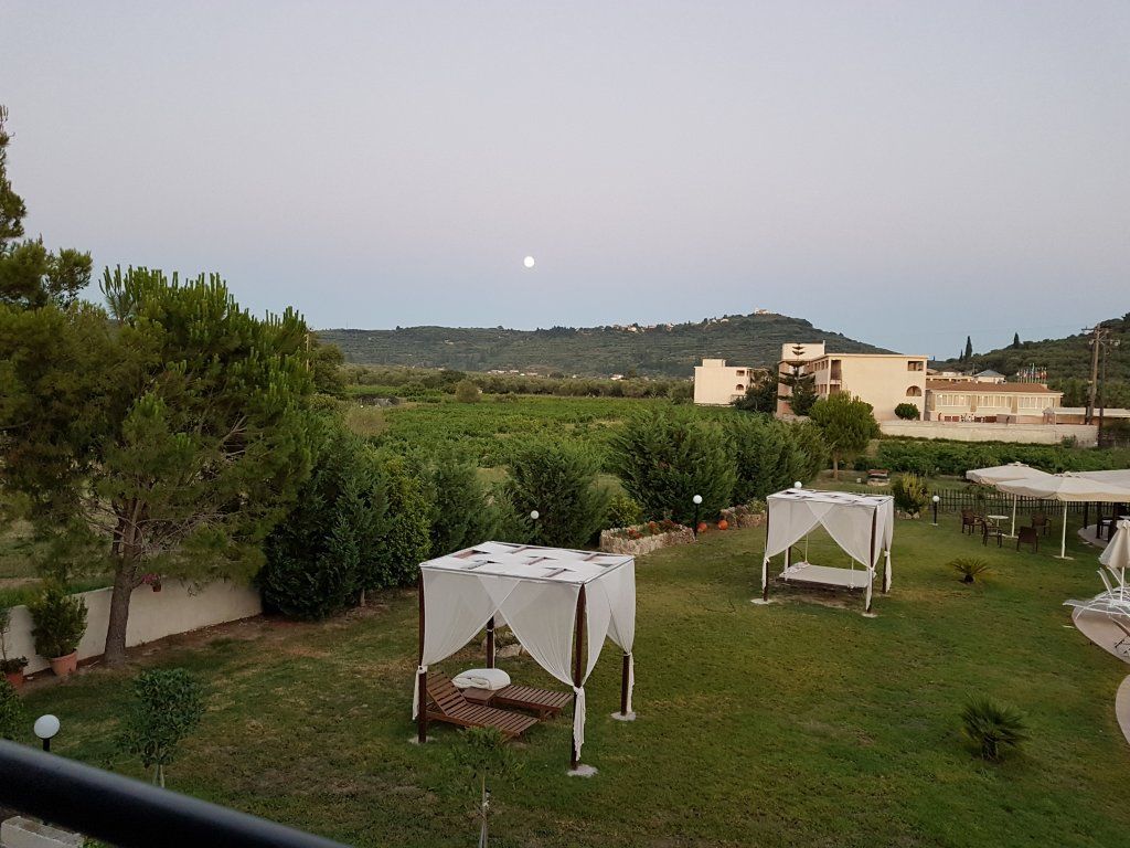 A courtyard with two white tents, a grassy area, and buildings in the background.