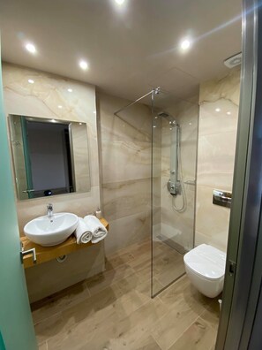 A modern bathroom with a glass-enclosed shower, a white sink, and a toilet. - Eleni's Garden & Castello Suites (Zakynthos)