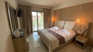 A hotel room with a large bed, a bedside table, a TV mounted on the wall, and a balcony with curtains. - Eleni's Garden & Castello Suites (Zakynthos)