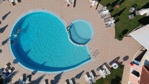 An aerial view of a swimming pool with a circular deck, surrounded by lounge chairs and umbrellas. - Eleni's Garden & Castello Suites (Zakynthos)