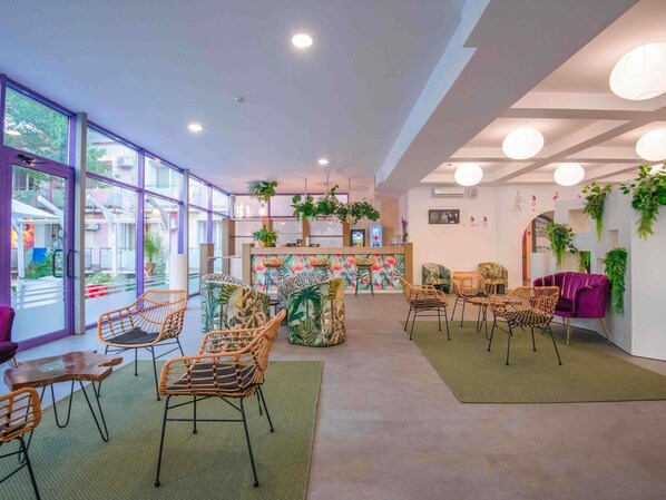 Een modern interieur met rieten stoelen, een receptiebalie en binnenshuis planten.
