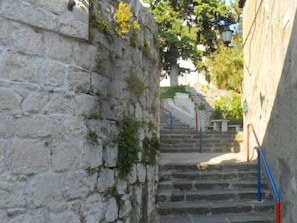 A stone staircase with a metal handrail leading up to a building entrance.