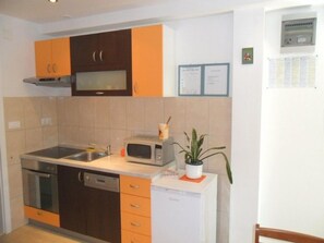 A compact kitchen with a dishwasher, microwave, and a small refrigerator. - Villa Dube (Split)