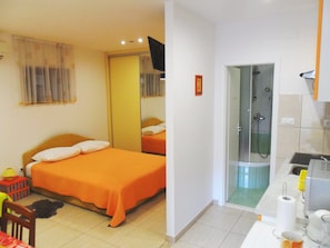 Une chambre d’hôtel comprenant un lit, un espace douche et une petite kitchenette.