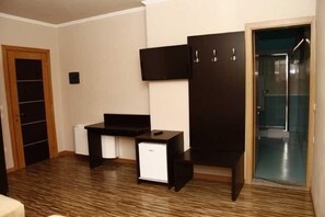 A room with a desk, a wardrobe, and a door leading to a bathroom.