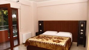 Quarto com cama, mesa de cabeceira, espelho e porta de vidro deslizante para área externa.