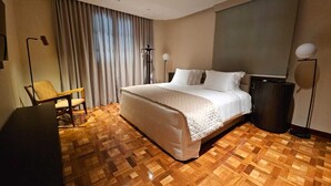 A hotel room with a large bed, a chair, a bedside table, and a floor lamp. - Glória Caxambu Resort & Convention (Caxambu)