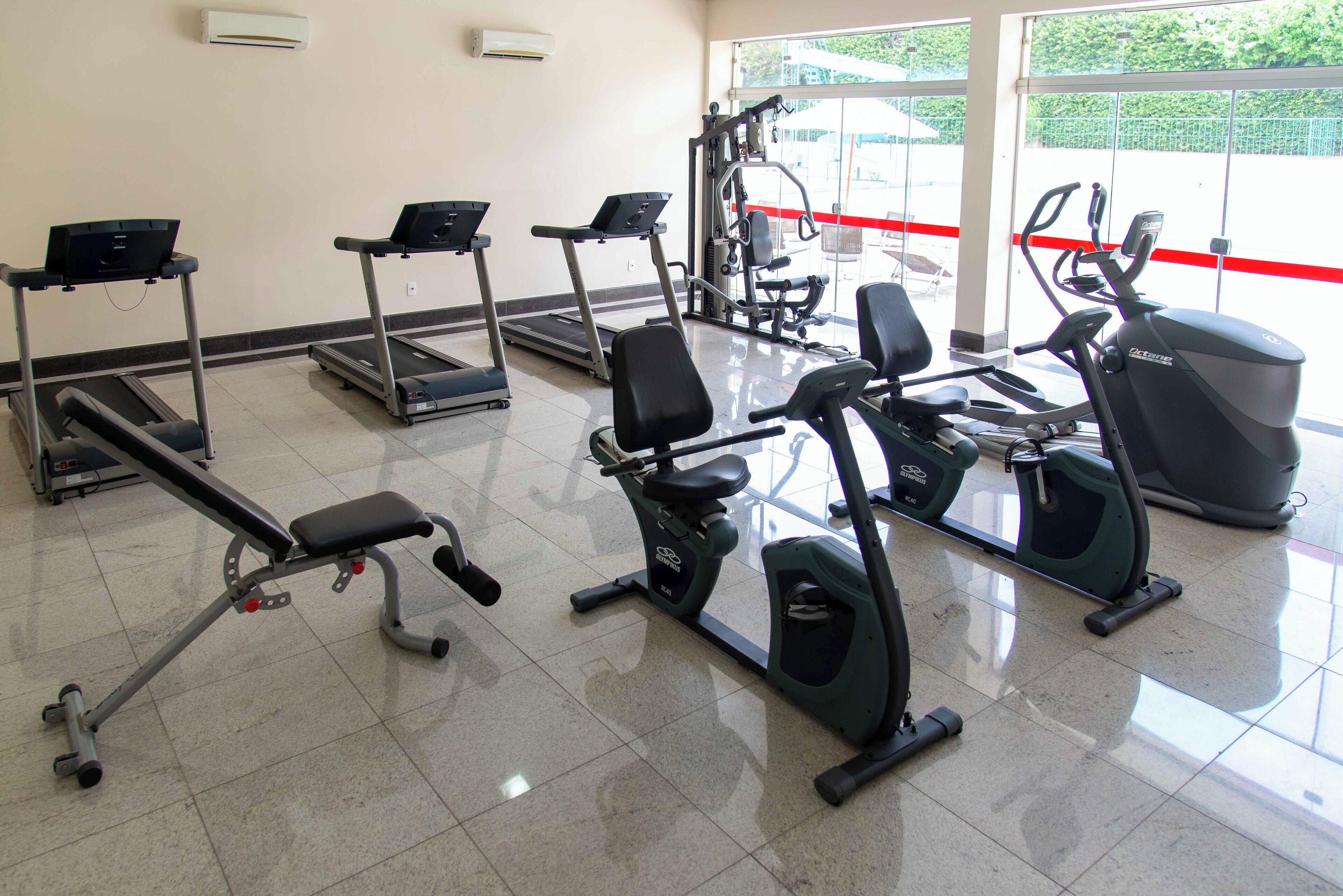 Un gimnasio con cintas de correr, elípticas y máquinas de pesas.
