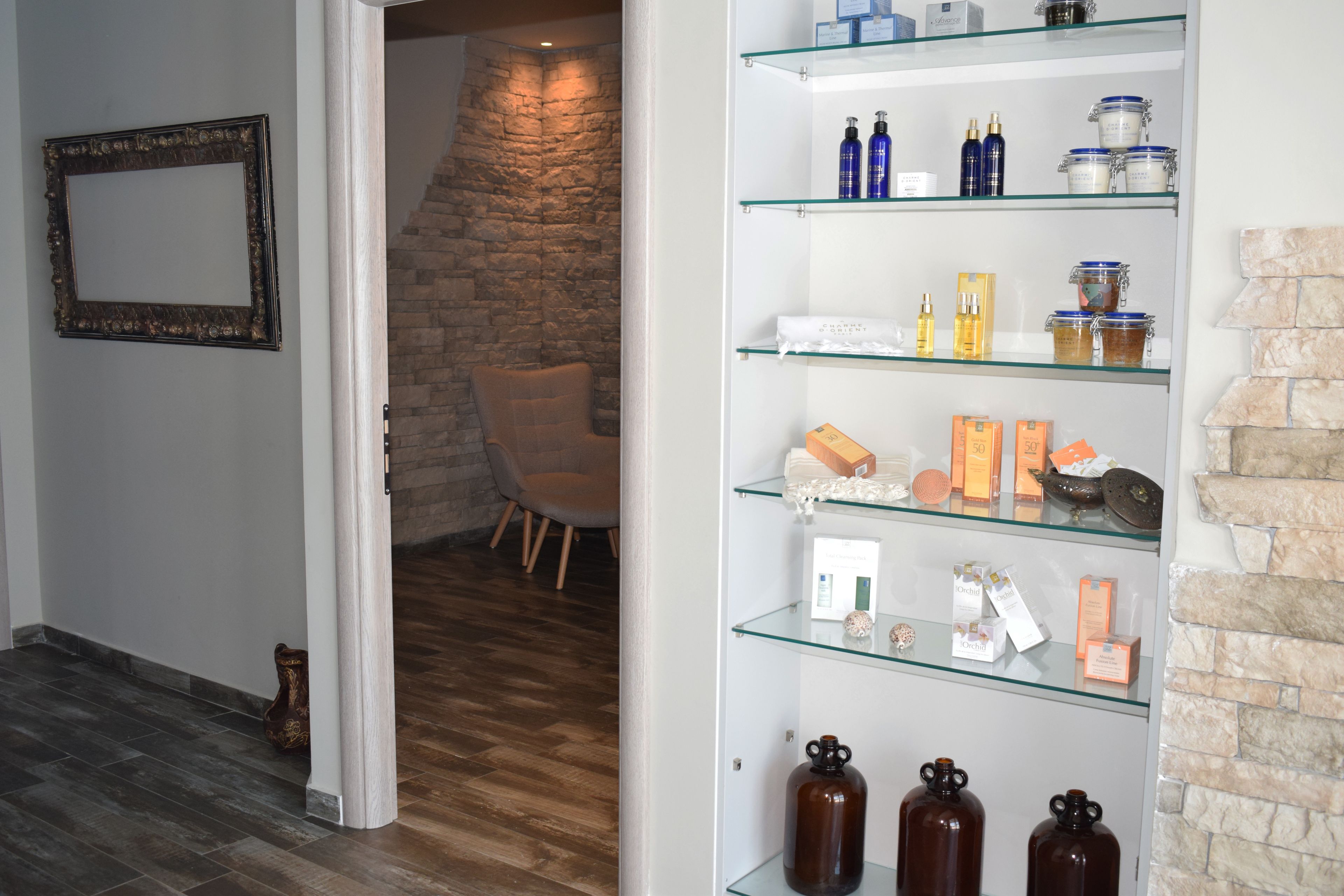A hallway with a glass display case containing various toiletries and a stone wall in the background.