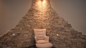 A chair in a corner with a stone wall and wooden flooring. - Myrtis (Agios Vasileios)