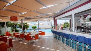 A covered outdoor area with tables and chairs, a pool, and a bar. - Myrtis (Agios Vasileios)