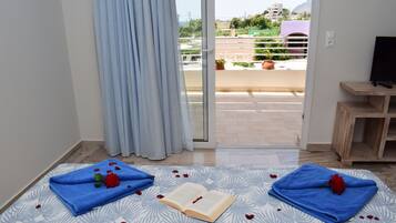 Una habitación con una cama, un libro y dos toallas decoradas con pétalos de rosa.
