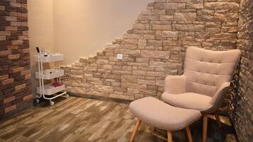 A room with a stone wall, a wooden floor, and a beige armchair.