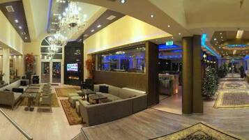 A spacious lobby with a seating area, a bar, and a Christmas tree.