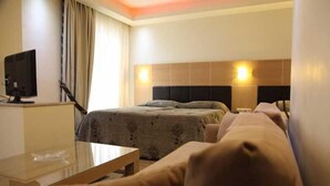 Ein Hotelzimmer mit einem Bett, einem Schreibtisch, einem Fernseher und zwei Wandleuchten.