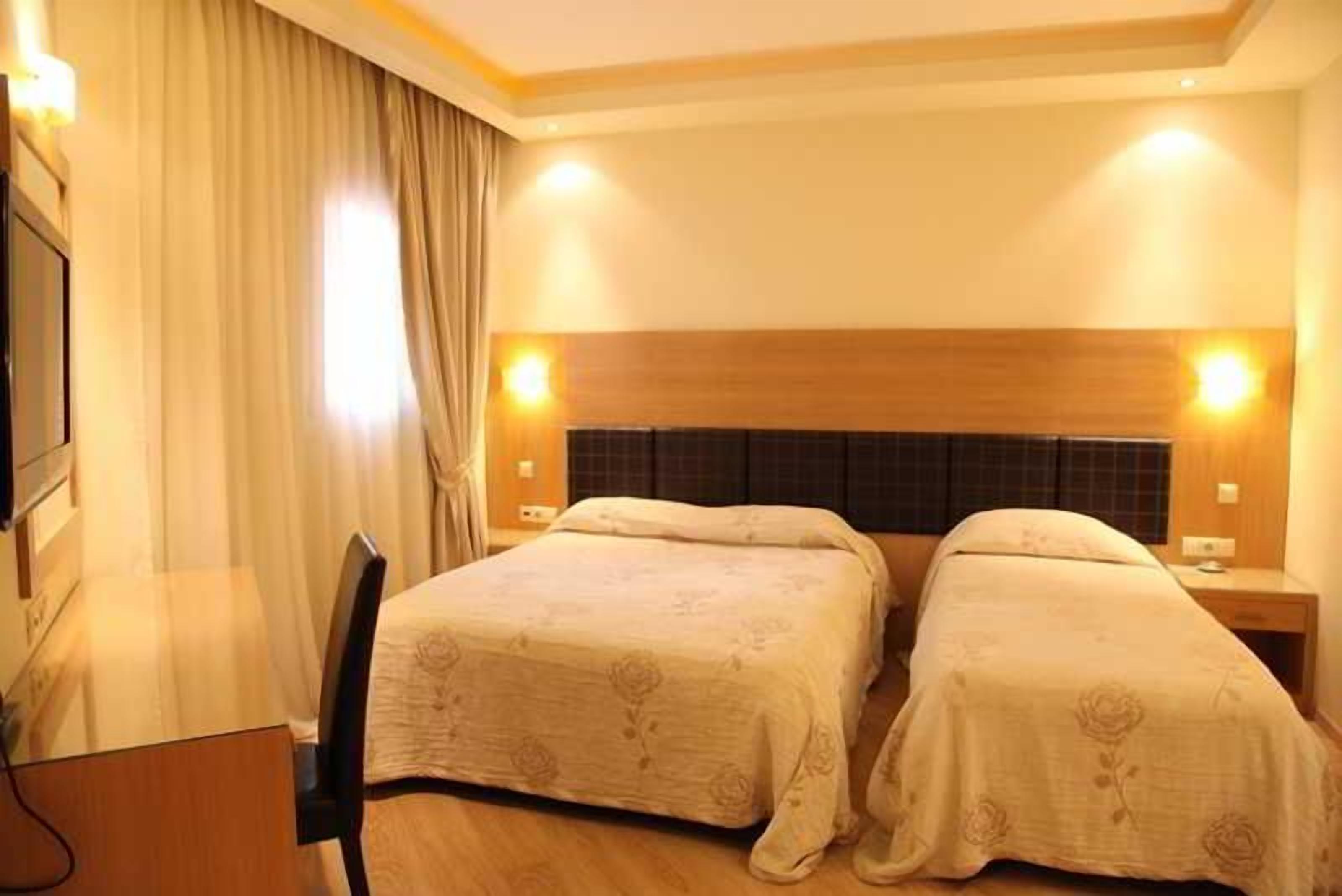 Een hotelkamer met twee bedden, een bureau en een stoel.