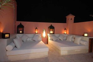 Two white sofas with cushions, each with a small table and a wall-mounted light. - Riad Anais (Marrakech)