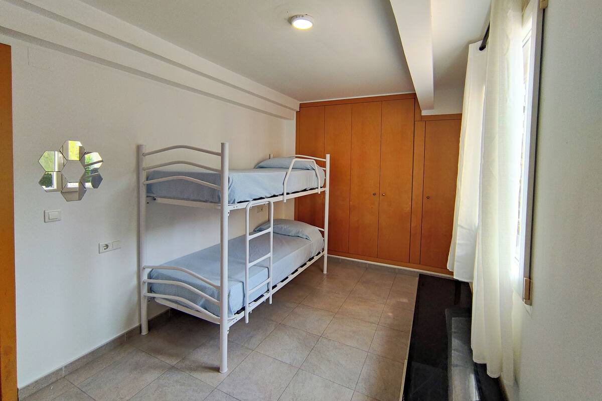 A room with bunk beds, wooden wardrobe, and a mirror on the wall.