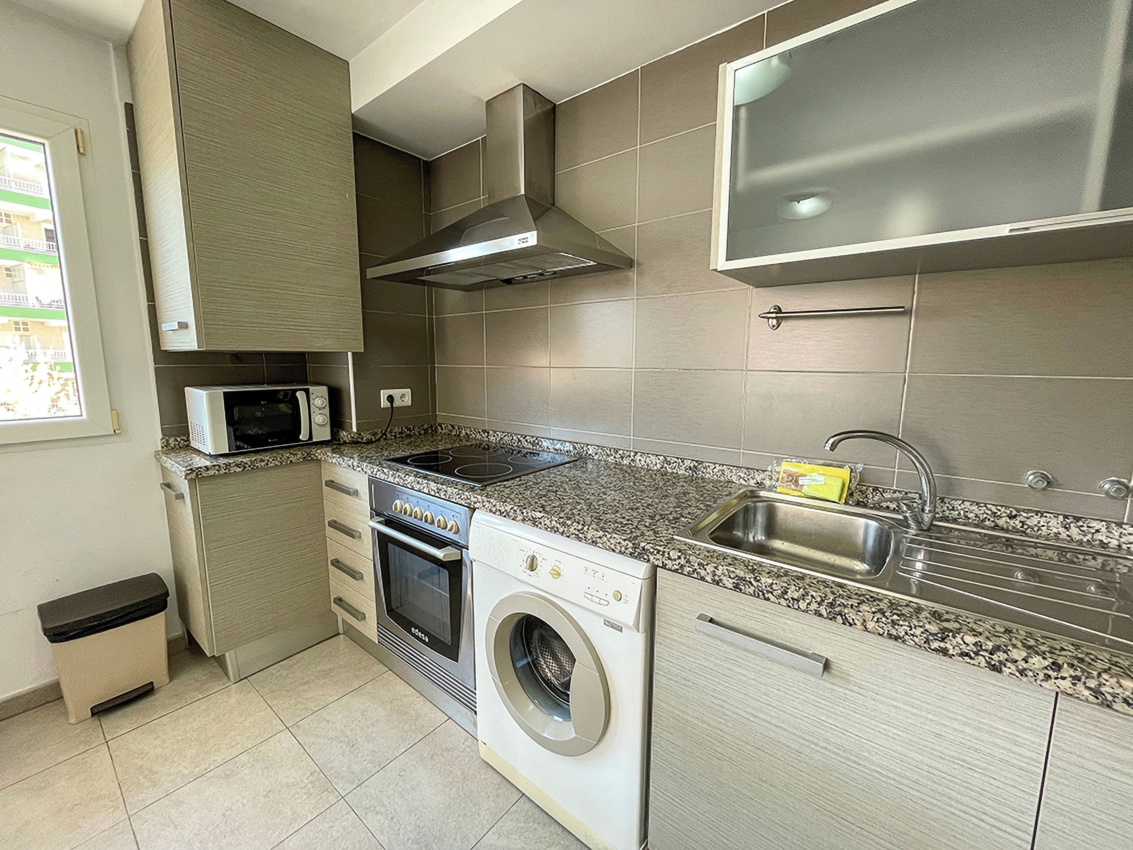 A compact kitchen with a microwave, stove, oven, and built-in washing machine.