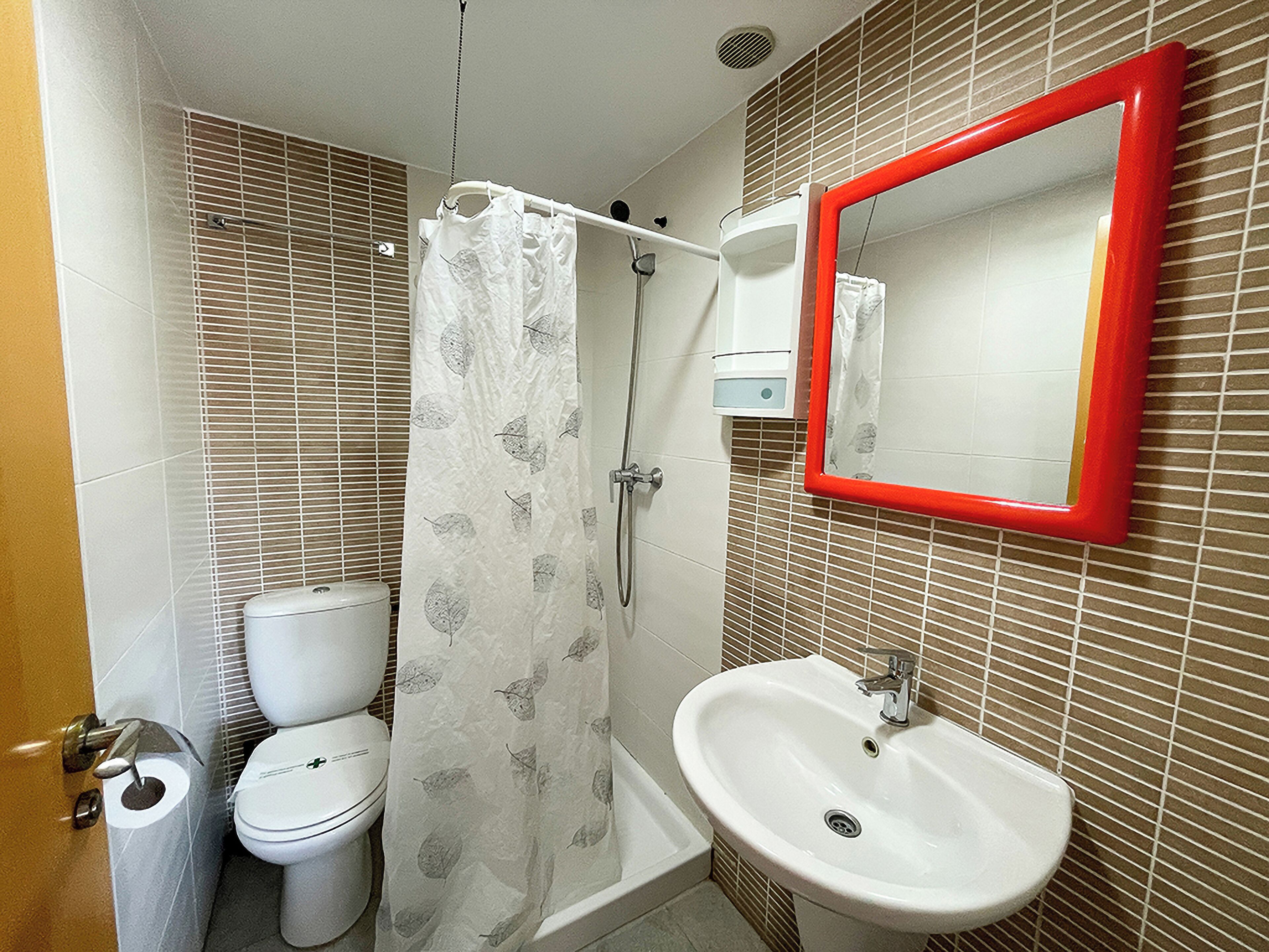 A bathroom with a toilet, shower, and sink.