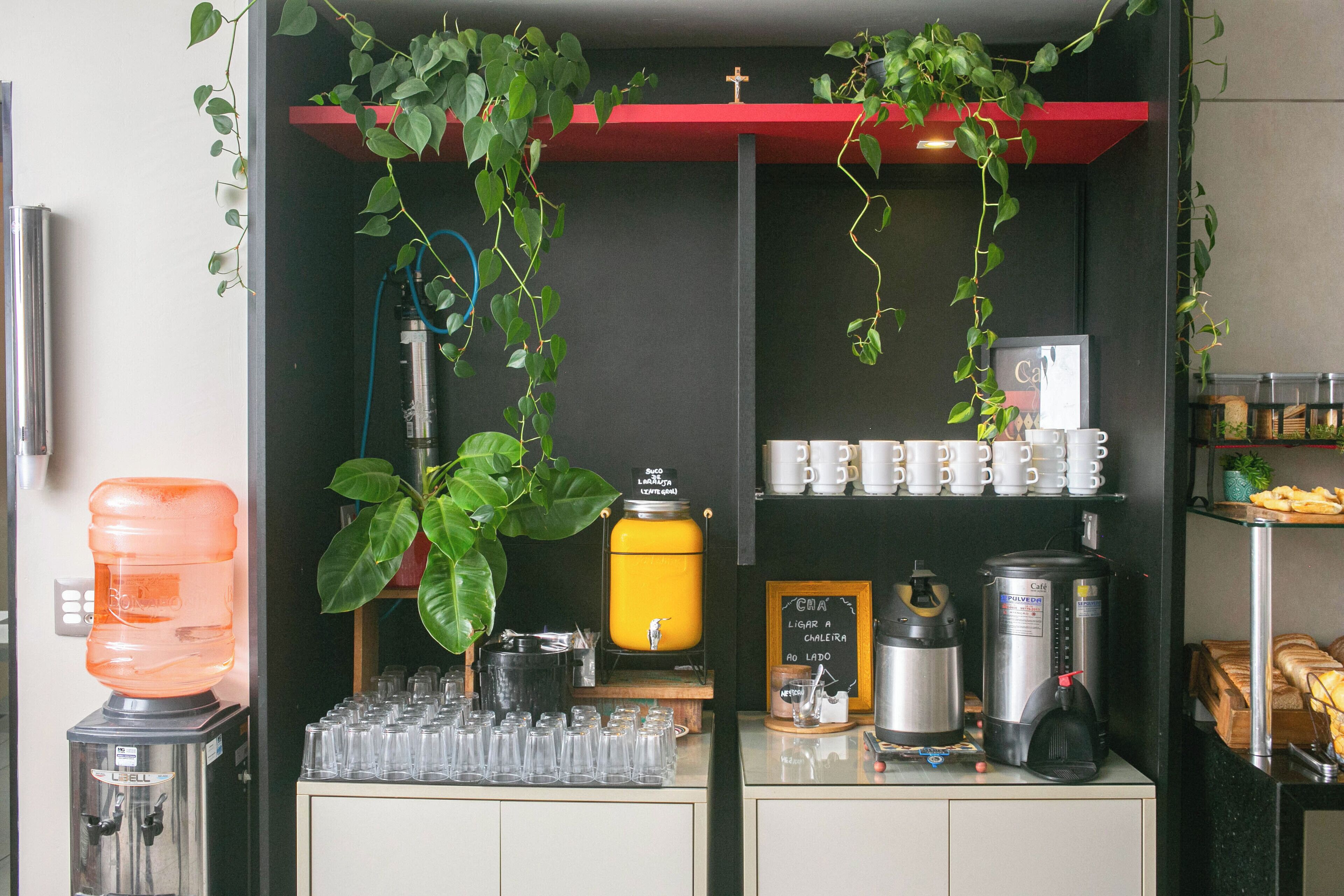 A coffee station with a water dispenser, coffee machine, and cups.